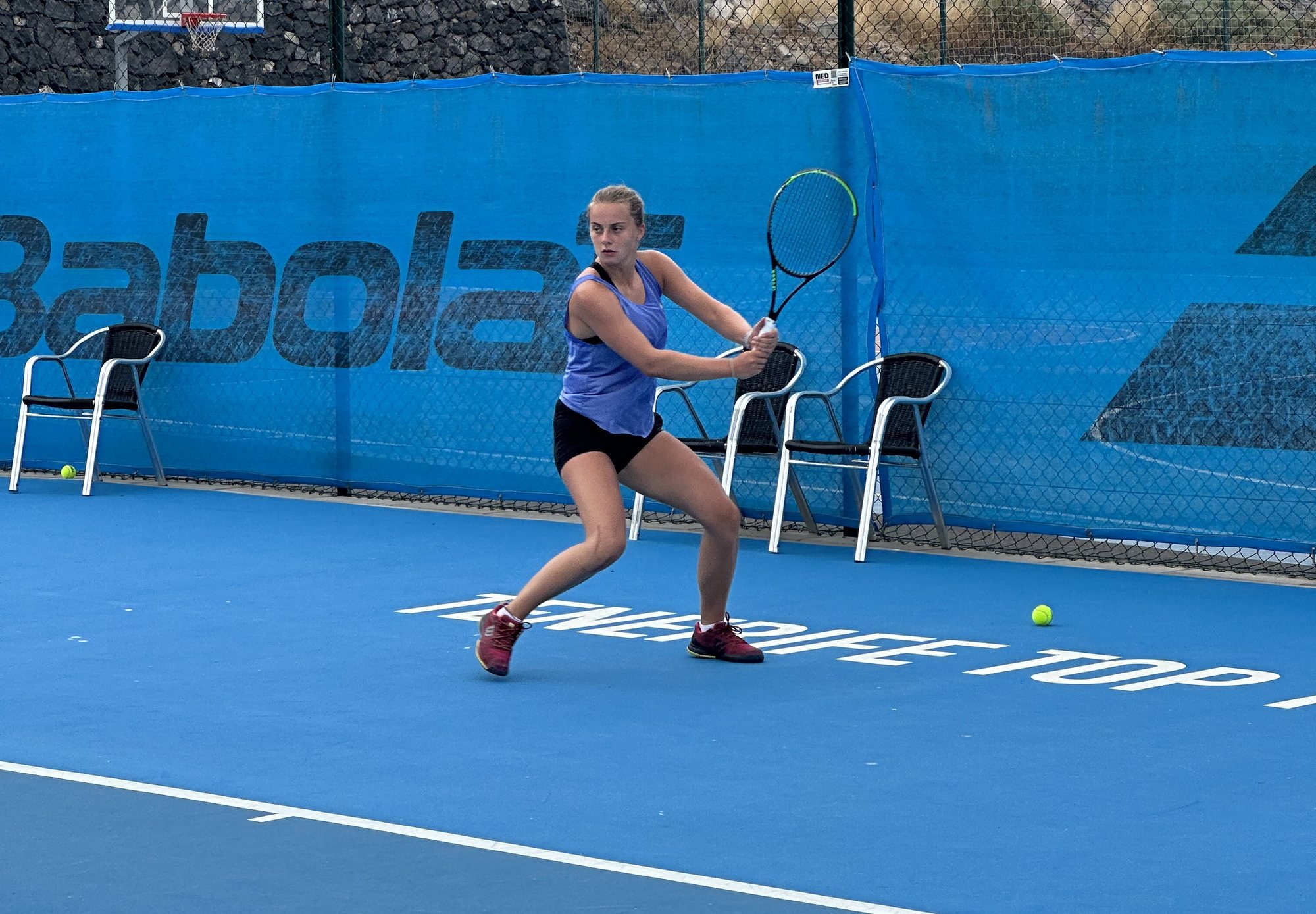 A player driving a two-handed backhand on the hard courts at T3
