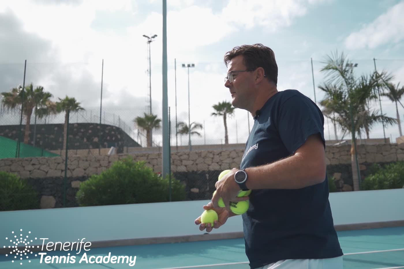 Carl Maes on the academy's outdoor hard courts in Tenerife, balls in hand between feeds