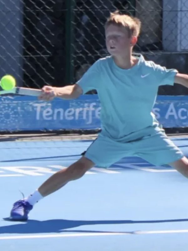A young player stretching for a forehand on the hard courts