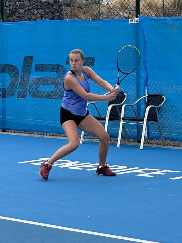 A junior player loading up a backhand on the hard courts at T3
